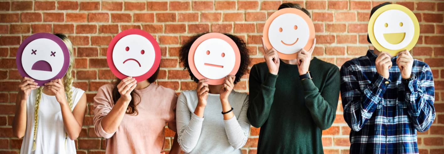 Menschen, die sich ausgedruckte Smilie-Gesichter vor den Kopf halten
