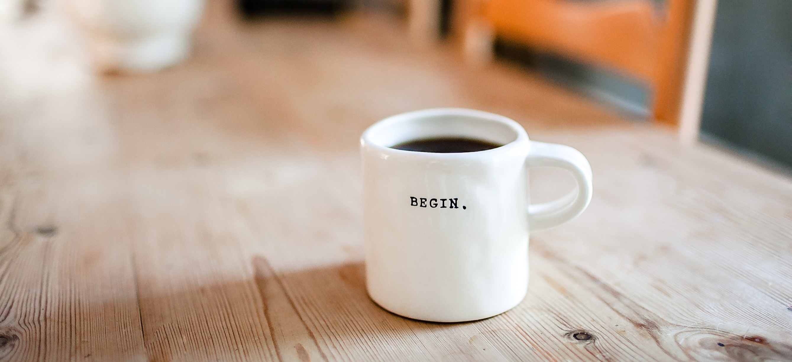 Tasse auf Tisch mit der Aufschrift „Begin”.