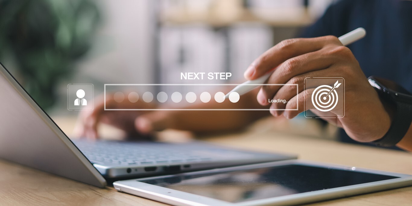 Geschäftsmann, der mit dem digitalen Fortschrittsbalken und der Next Step-Schnittstelle auf Laptop und Tablet interagiert.